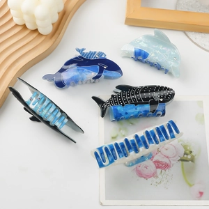 Blue ocean-themed hair claws featuring whale and dolphin shapes on a white background