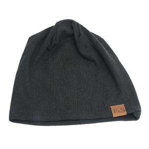 Close-up of black ribbed knit beanie with brown leather F&S label on white background