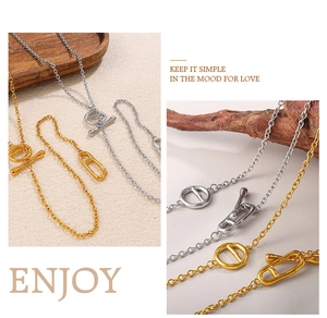 Detailed view of minimalist gold and silver OT buckle necklaces on a textured wood display