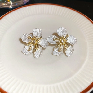 Macro view of textured floral stud earrings with sparkling diamonds on a ceramic plate