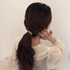 Elegant gold woven texture elastic hair tie shown on model for stylish ponytail hairstyles