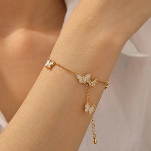 Detailed view of a gold-tone butterfly charm bracelet worn on a woman wrist