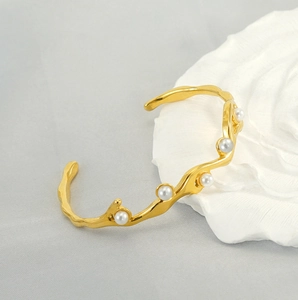 Dettaglio di un bracciale placcato oro 18k con trama lava e perle artificiali