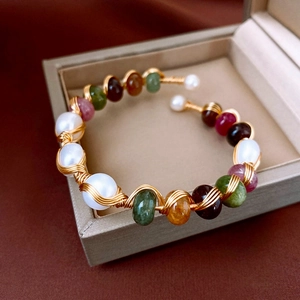 Detail of beaded pearl cuff with multicolored gemstones on a velvet jewelry box edge