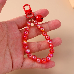 Close-up of red beaded keychain with metallic bell charm and glossy finish beads