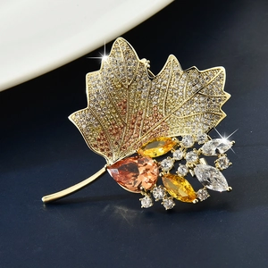 Detailed shot of maple leaf brooch with sparkling crystals and golden metallic finish