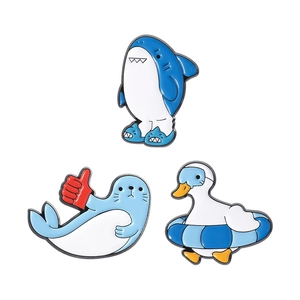 Cute blue animal enamel pins featuring a shark, seal, and duck on a white background