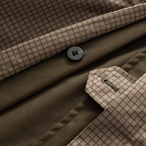 Detail of tan faux fur coat featuring brown checkered lining and matte black button