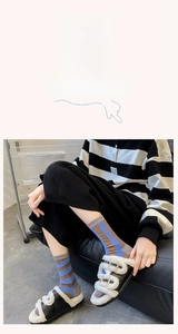 Detailed shot of striped cotton mid-calf socks paired with plush faux fur double-buckle sandals
