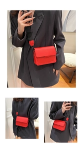 Detail of red PU leather crossbody bag with black wide strap and flap closure