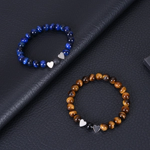 Detailed shot of tiger eye stone bead bracelets with silver heart pendants on black leather