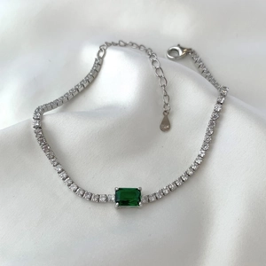 Macro detail of S925 silver tennis bracelet with emerald cut green stone and 925 hallmark
