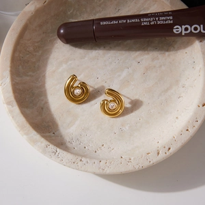 Gros plan de boucles d'oreilles créoles dorées torsadées avec zircons sur un plateau