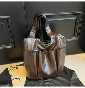 Detail of dark brown vintage faux leather tote bag showing multiple external pockets