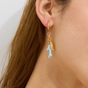 Close-up of gold hoop earrings with light blue coral and shell charms on model