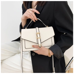 Detail of white leather shoulder bag featuring gold buckle and black trim accents