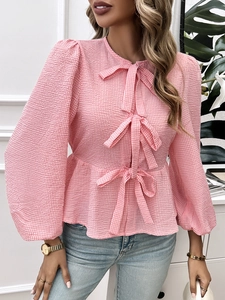 Detailed view of pink plaid blouse featuring puff sleeves and three front decorative bows