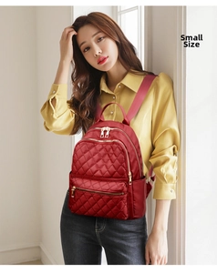 Detail of red quilted nylon backpack showing gold zippers and stylish diamond pattern