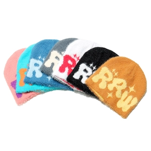 Detailed pile of thick knit beanies in multiple colors with faux mink texture and letters