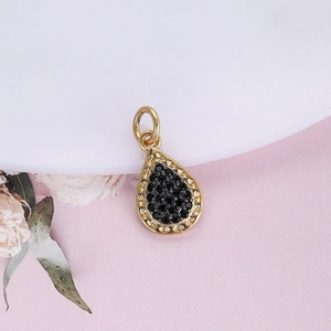 Close-up of a gold waterdrop pendant with black pave crystals and filigree edges