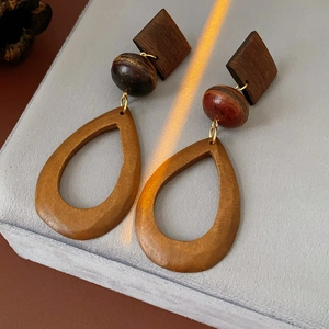 Detail of wooden drop earrings with rhombus and bead parts on a velvet jewelry stand