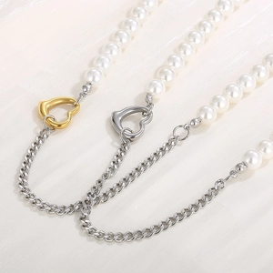 Detail of mixed pearl and Cuban link necklaces with heart-shaped metal clasps on fabric