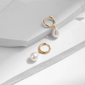 Elegante Goldene Ohrringe mit weißen Tropfenperlen auf geometrischem Steinhintergrund