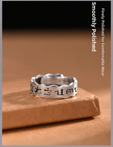 Macro detail of wave-edged silver ring featuring engraved Buddhist mantra and vintage finish