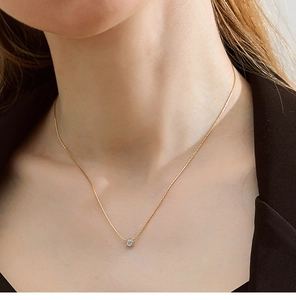 Detailed view of single zircon pendant on 18K gold plated bamboo chain worn by model