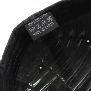 Close-up of the black cotton baseball cap interior showing the 100% cotton washing label