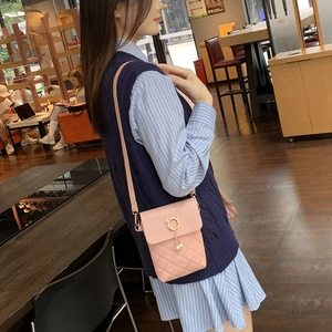 Pink quilted crossbody bag with golden cat hardware and pearl tassel shown in a cafe