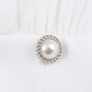 Haut blanc élégant doté d'un bouton perle avec bordure décorative en chaîne argentée