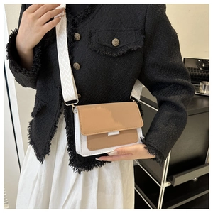 Detail of a brown and white crossbody bag featuring a patterned wide fabric shoulder strap
