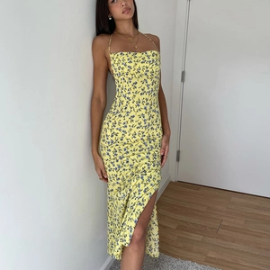Detail of yellow floral midi dress featuring side slit and delicate blue flower pattern