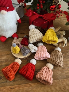 Detailed view of colorful mini knitted Christmas hats with pom-poms on a rustic background