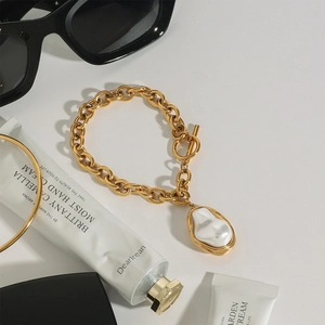 Detail of 18k gold stainless steel chain bracelet with a baroque pearl and OT toggle