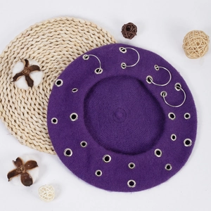 Top view of a purple beret with silver metal eyelets and rings on a clean background