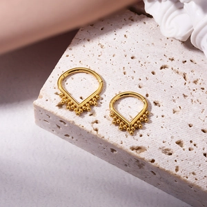 Golden teardrop G23 titanium nose ring with decorative bead accents on stone