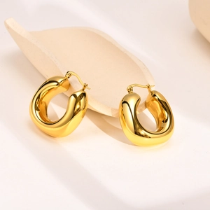 Polished hollow chunky teardrop earrings in gold finish on a minimalist display