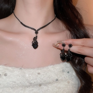 Detailed view of model wearing black heart pendant necklace and matching stud earrings set