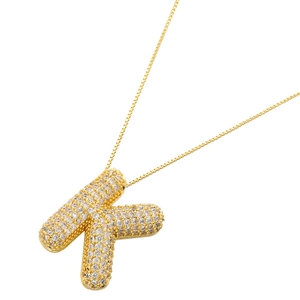 Macro detail of gold-plated balloon letter K pendant with sparkling pavé zircons