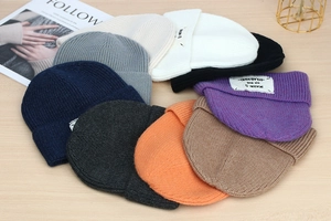 Overhead view of various colored ribbed knit beanies arranged on a wooden table