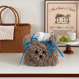 Detail of cute brown plush puppy tissue box cover with a blue ribbon in home setting