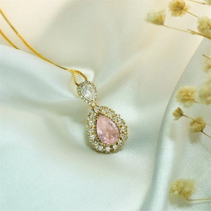 Close-up of pink teardrop pendant with micro-pave crystals on a gold box chain