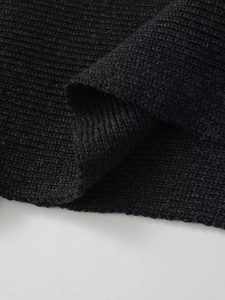 Detail shot of black wool-blend knitted fabric showing the premium ribbed weave texture