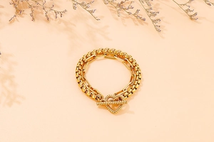 Dettaglio del bracciale dorato a doppio strato con chiusura a T a forma di cuore