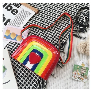 Detailed close-up of rainbow striped crossbody bag with heart patch on mesh background