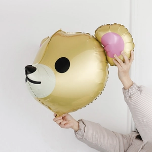 Detailed view of a golden bear head foil balloon held by hand for party decoration
