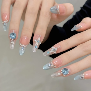 Detailansicht der Stiletto-Nägel mit blauen Edelsteinen und silbernen Blumenakzenten