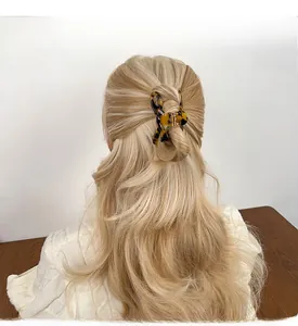 Detail view of large tortoiseshell bow claw clip styling a half-up hair look for women
